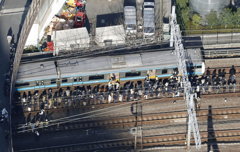 JR東日本16日因停電一度停駛，有乘客自停於JR京濱東北線的列車下車，步行於鐵道上。（共同社）