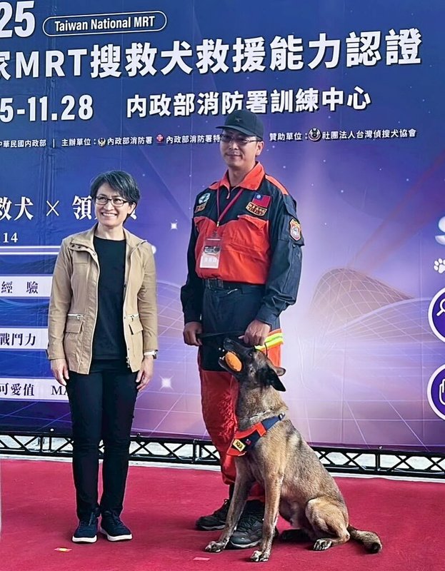 新北市府消防局搜救犬Aqua在「IRO國際搜救犬世界盃」瓦礫堆搜索項目獲得世界盃第5名，17日在新北市被授階為分隊長。圖為114年11月25日，Aqua（中）參加「2025年國家MRT（Mission Readiness Test）搜救犬救援能力認證」與副總統蕭美琴（左）合影，右為領犬員吳惟逸。（新北市府消防局提供）中央社記者黃旭昇新北傳真  115年1月17日