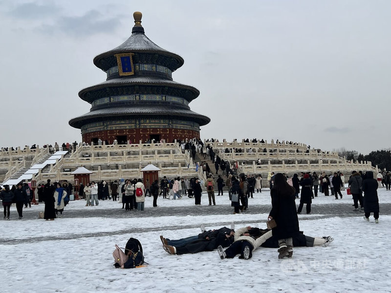 17日晚間北京市區下雪，圖為18日北京天壇的遊客把握北京難得的下雪時光，躺在地上盡享古韻冬景。中央社記者呂佳蓉北京攝 115年1月18日