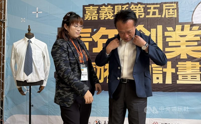 嘉義縣政府21日舉辦「第5屆嘉義縣青年創業獎勵補助」計畫記者會，並邀請勇奪2025年世界洋服大賽女裝裁剪比賽青年組金牌的「連衣連文創工作室」負責人陳詩婷（左）現身分享。陳詩婷特別致贈一套親手量身訂製的手工西裝給嘉義縣長翁章梁（右）。中央社記者蔡智明攝　115年1月21日