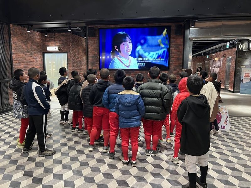 世界12強棒球賽冠軍總教練曾豪駒招待新竹縣小球員觀看紀錄片「冠軍之路」，開演前小球員聚在一起看廳外播放的預告片。（球芽基金提供）中央社記者蘇志畬傳真　115年1月22日