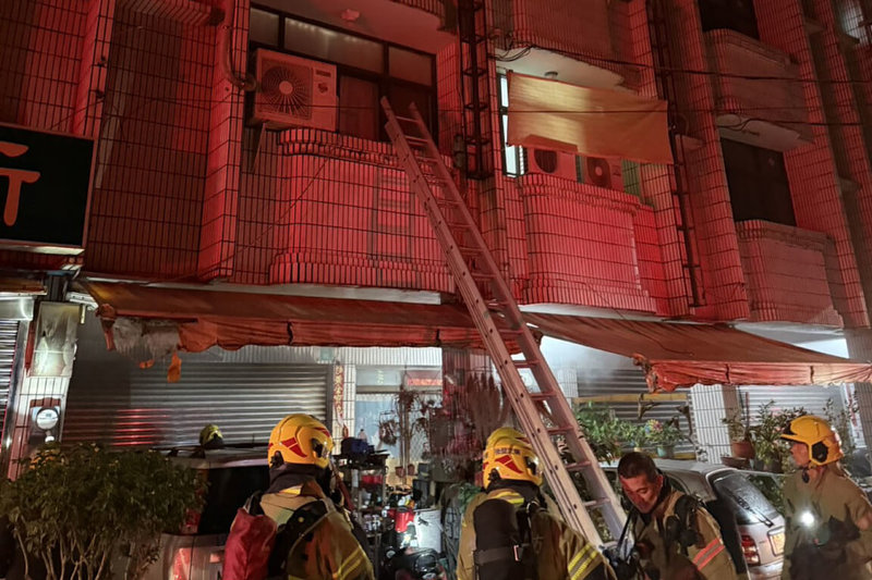台南市白河區一處透天厝民宅22日凌晨發生火警，濃煙觸動住宅警報器提醒在2樓熟睡2人，及時撤出至陽台處，由消防人員架梯協助引導逃出。（消防局提供）中央社記者楊思瑞傳真 115年1月22日