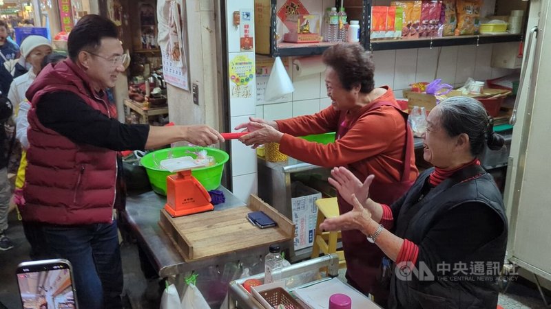 中國國民黨台中市長提名人選未定，爭取提名的立法院副院長江啟臣（左），25日前往東區建國市場發送春聯，並與顧客與攤商打招呼、請託。中央社記者蘇木春攝　115年1月25日