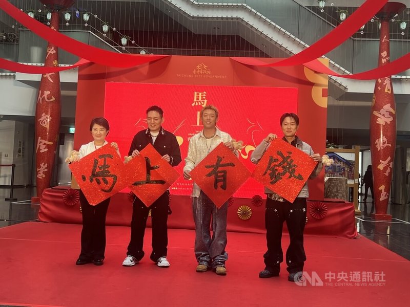 台中市政府26日辦迎新揮毫贈春聯活動,台中市長盧秀燕(左1)與在地樂團玖壹壹成員春風(左2起)、健志與洋蔥合力揮毫「馬上有錢」。中央社記者郝雪卿攝 115年1月26日