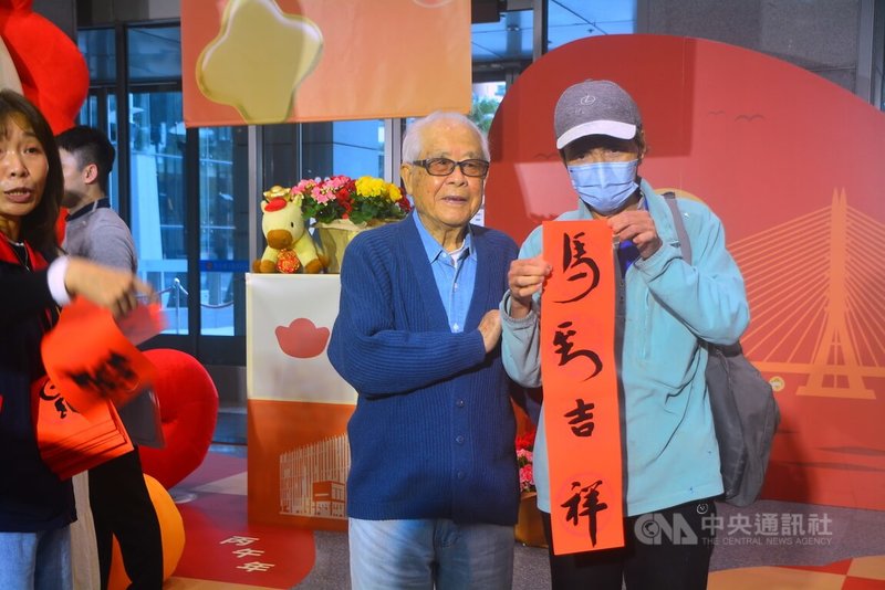 新北春聯發布記者會27日於市府大廳舉行；百歲人瑞書法家沈軏（右2）揮毫，贈送春聯給洽公的民眾。中央社記者黃旭昇新北攝 　115年1月27日