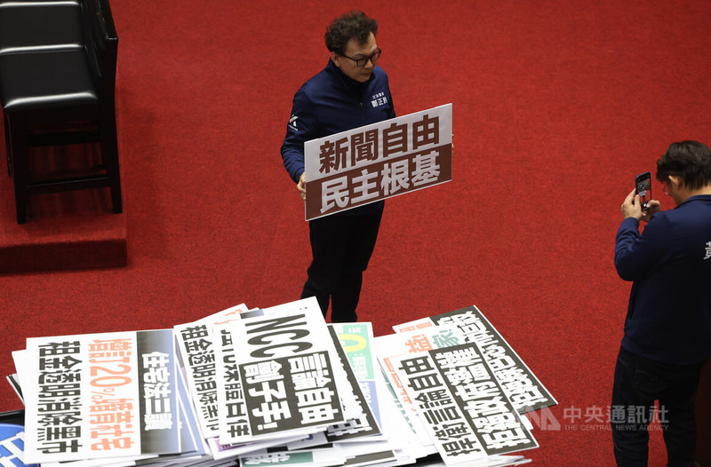 立法院會30日下午三讀通過衛星廣播電視法部分條文修正案,國民黨立委鄭正鈐(中)隨後拿起寫有「新聞自由」等字句的標語在議場中留影。中央社記者趙世勳攝 115年1月30日