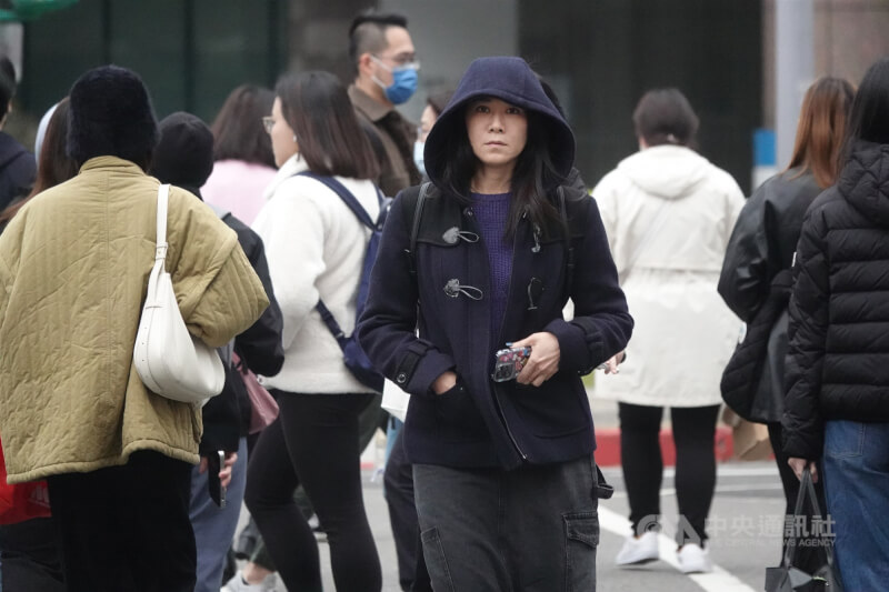 中央氣象署指出，31日下半天至晚間鋒面通過及冷空氣南下，北部及宜蘭轉涼。圖為台北市信義區街上民眾穿著大衣禦寒。（中央社檔案照片）
