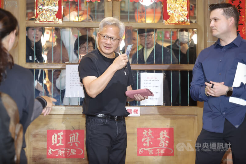 輝達（NVIDIA）執行長黃仁勳（中）31日晚間在台北宴請台灣供應鏈夥伴，在店外與粉絲互動時逗趣表示，幫粉絲簽錢包，那就得拿錢送給小孩子，或是交給店家當小費，隨後真的從錢包內拿出鈔票交給在場小朋友。中央社記者翁睿坤攝　115年1月31日