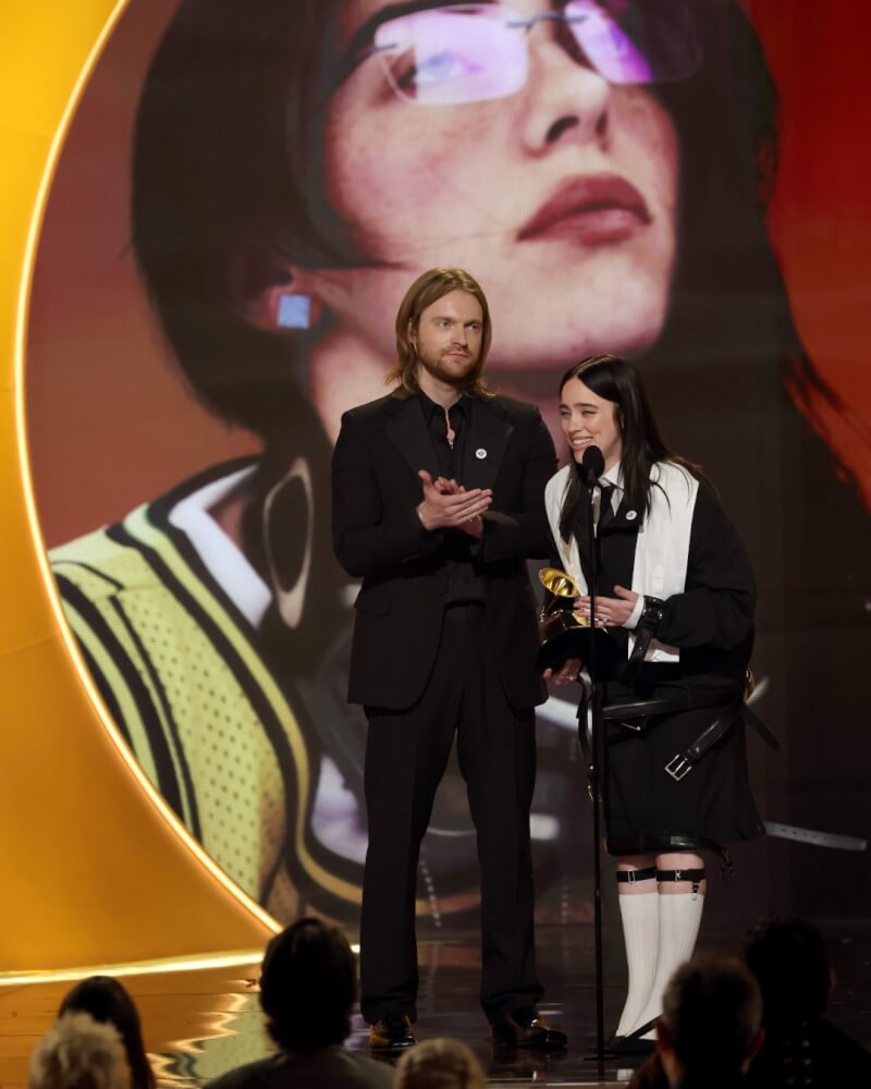 美國流行歌手怪奇比莉（右）與哥哥歐康奈爾（左）1日以歌曲Wildflower榮獲葛萊美最佳年度歌曲獎。（圖取自facebook.com/GRAMMYS）