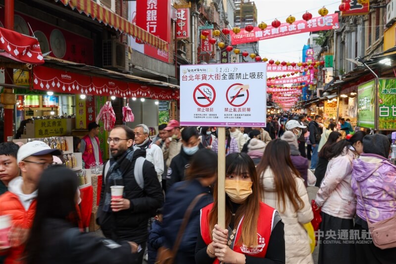 圖為去年台北年貨大街首度實施全面禁菸政策,市府安排人員手舉牌沿街宣導。(中央社檔案照片)