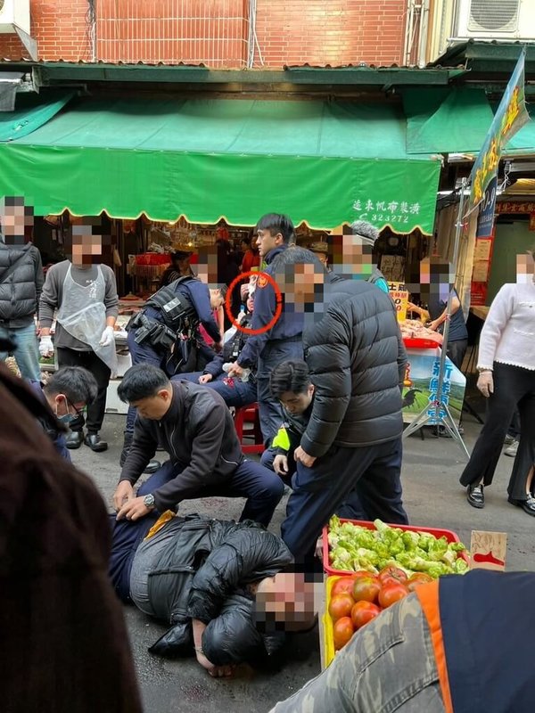 40歲鍾姓男子（前倒地者）4日上午在苗栗市南苗市場持刀向攤商借手機未果，持續滯留攤位旁引發恐慌，隨後又攻擊砍傷到場處理員警（後紅圈處）。警方情急開槍制伏，鍾嫌胸部中彈送醫不治，案由檢警偵辦中。（民眾提供）中央社記者管瑞平傳真 115年2月4日