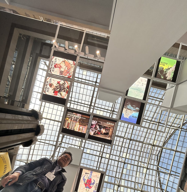 台北國際書展九歌出版展位,去年獲書展「最佳展位設計獎」中小型展位組銀獎,今年將創意放在少有人注意的「上空」,抬頭可見多幅設計精美優雅的文學書封面,有些讀者將手機放在地上並設定倒數自拍,景深十足。中央社記者邱祖胤攝 115年2月4日