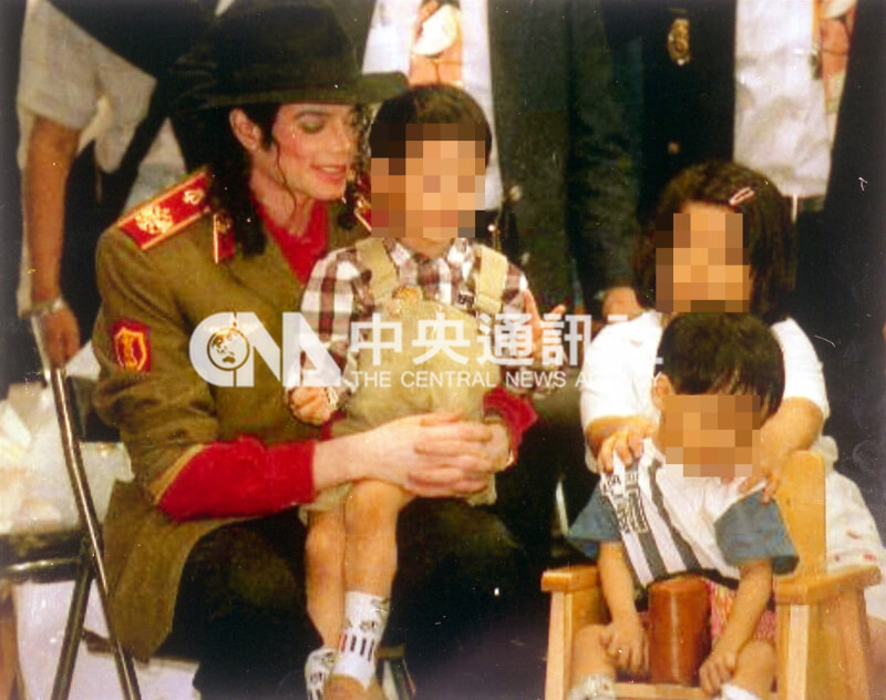 麥可傑克森1996年訪問高雄市立無障礙之家，親切地抱起3歲小朋友坐在他腿上。（中央社檔案照片）