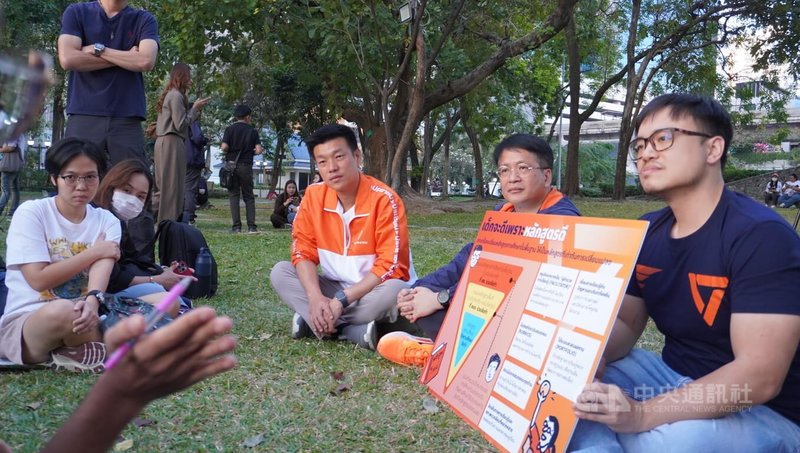 不同於傳統的造勢活動，選前民調支持度最告、泰國人民黨第一順位總理候選人納塔彭（橘衣）與選民在草地上並肩而坐近距離聆聽選民需求。中央社記者李宗憲曼谷攝　115年2月6日