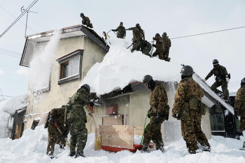 日本自衛隊員7日在青森市清除屋頂積雪。（共同社）