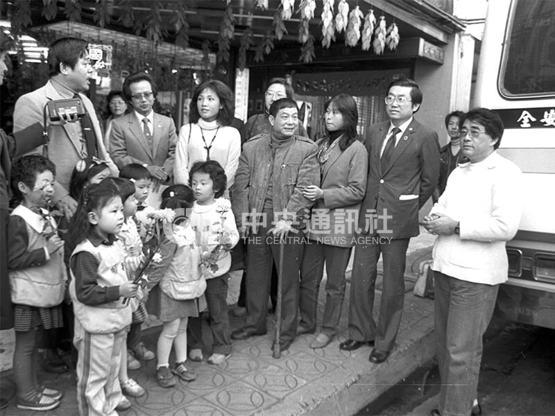 鄧禹平（右4）從未去過阿里山，晚年病弱體衰。音樂家林二（右1）、中華民國工商管理學會理事長范光陵（右2）等人，陪同鄧禹平上山高唱《高山青》。圖為出發前，鄧禹平與歌手王海玲（右5）接受小朋友獻花。中央社記者馮國鏘攝　72年12月12日