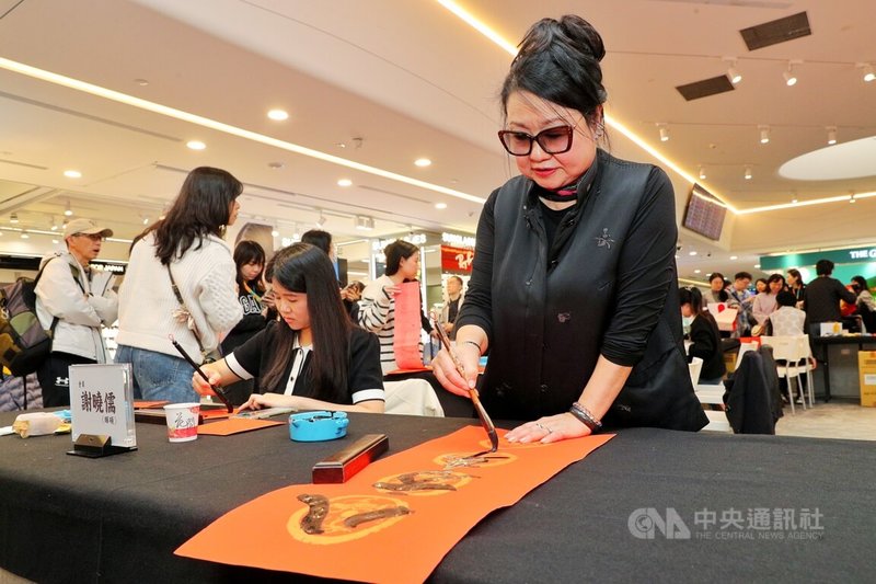 桃園國際機場采盟免稅店12日在第二航廈管制區內的台灣好廣場舉辦「馬耀新程」迎春揮毫活動，台灣墨秀書道會師生即興寫春聯。另外2月12日至3月3日期間也將設置旅客揮毫體驗區。中央社記者吳睿騏桃園機場攝　115年2月12日