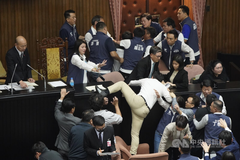 立法院於民國113年5月17日審議國會職權相關法案，在處理報告事項逕付二讀、進行表決時，民進黨立委郭國文（卡其褲）試圖翻越突襲主席台，被國民黨立委攔下。（中央社檔案照片）