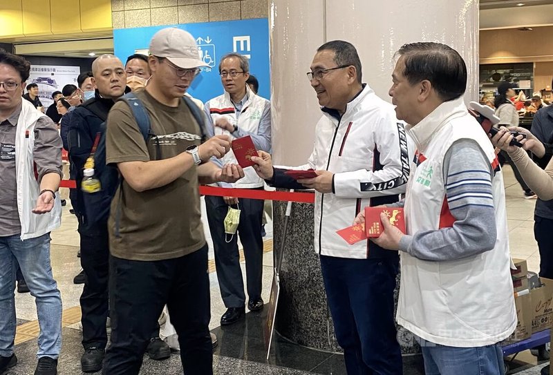 新北市長侯友宜(前右2)13日傍晚在交通局長鍾鳴時(前右)陪同下前往視察板橋車站春節疏運情形,並發放福袋向民眾拜早年。中央社記者黃旭昇攝 115年2月13日