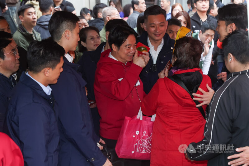 總統賴清德（中紅衣者）17日上午在台北市艋舺龍山寺參香並發放福袋時，比讚祝福民眾新年快樂。 中央社記者吳家昇攝 115年2月17日