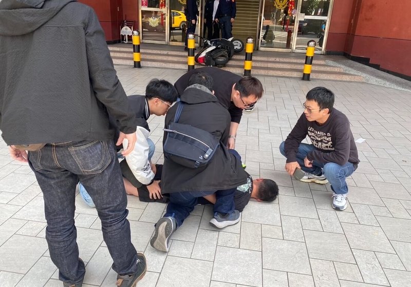 32歲吳姓男子（趴地者）23日下午騎乘機車衝向基隆市警察局，機車卡在大門口階梯倒下，員警將吳男壓制在地，上銬帶至分局製作筆錄；吳男面對警方詢問精神恍惚，拒絕配合毒品唾液快篩。（讀者提供）中央社記者王朝鈺傳真　115年2月23日