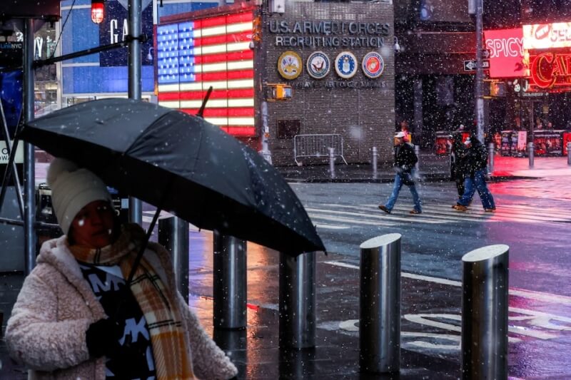 紐約時代廣場民眾撐傘擋雪。(路透社)