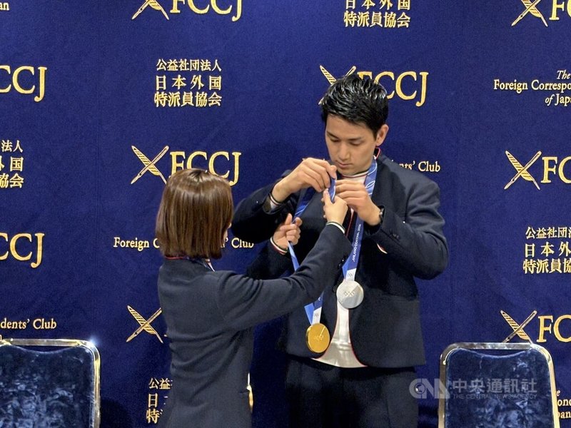 米蘭冬奧落幕,花式滑冰雙人組合「璃來龍」三浦璃來與木原龍一25日下午出席日本外國特派員協會記者會,三浦細心替木原整理獎牌。中央社記者戴雅真東京攝 115年2月25日