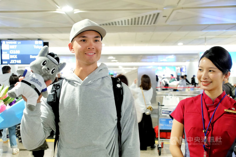 效力美國職棒大聯盟克里夫蘭守護者隊的台美混血好手「費仔」費柴德（Stuart Fairchild）（左）26日晚間搭機抵台，在機場開心收下中職吉祥物「歐告」娃娃。中央社記者吳睿騏桃園機場攝　115年2月26日