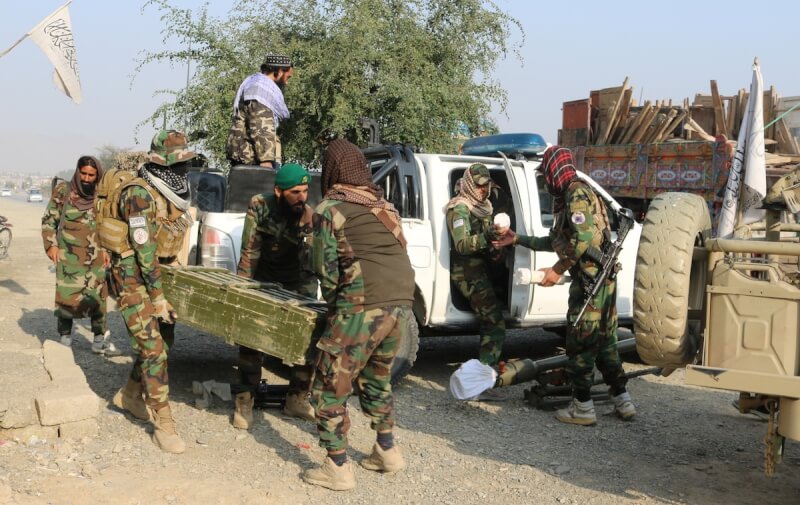 阿富汗邊境的塔利班士兵27日搬運裝有武器的箱子。（路透社）