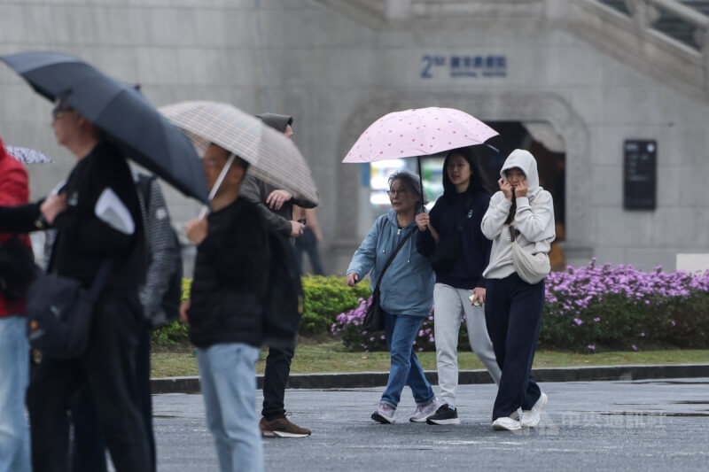圖為台北市在中正紀念堂旅遊的民眾，用外套蓋住頭部遮風避雨。（中央社檔案照片）