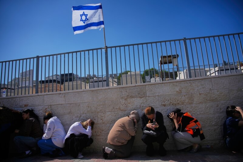 以色列民眾2日悼念在伊朗飛彈攻擊中喪生的罹難者時，又遇到空襲警報響起。（美聯社）