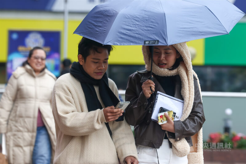 台北市中正區民眾撐傘穿著保暖衣物禦寒。（中央社檔案照片）