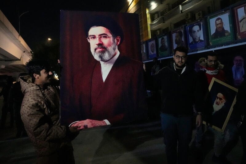 伊拉克民眾9日手持穆吉塔巴．哈米尼的畫像，支持他接任伊朗新任最高領袖。（美聯社）