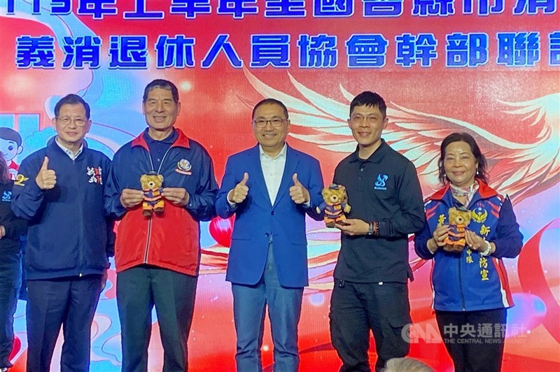 新北市長侯友宜（中）13日晚間出席新北市消防及義消人員回娘家暨全國退消協會幹部聯誼會，會中頒發「消防家庭貢獻獎」給義消特搜大隊黃春財（左2）一家。左為新北市消防局長陳崇岳。 中央社記者黃旭昇攝　115年3月13日