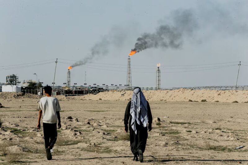 圖為9日伊拉克蘇貝爾油田附近農地可見遠方天然氣燃燒火光。（路透社）