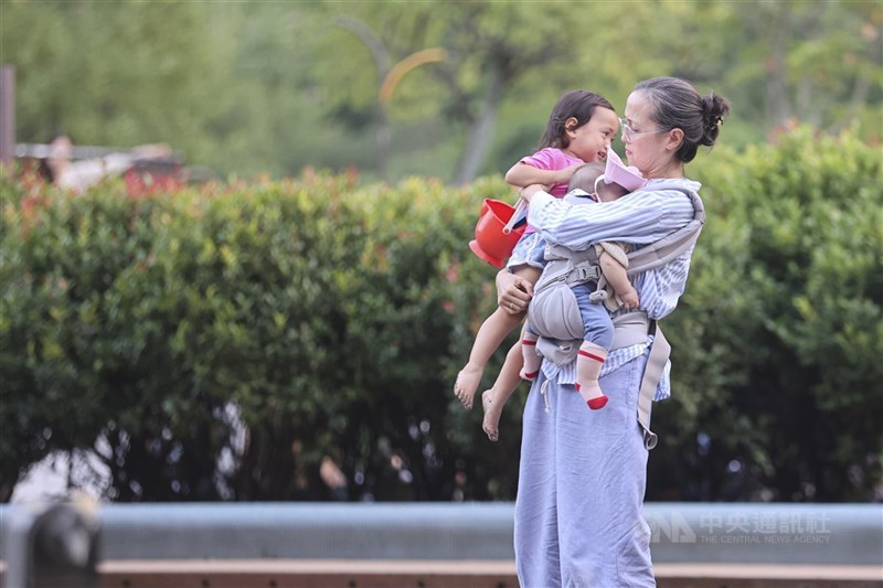 圖為家長抱著孩子到大安森林公園散心。（中央社檔案照片）