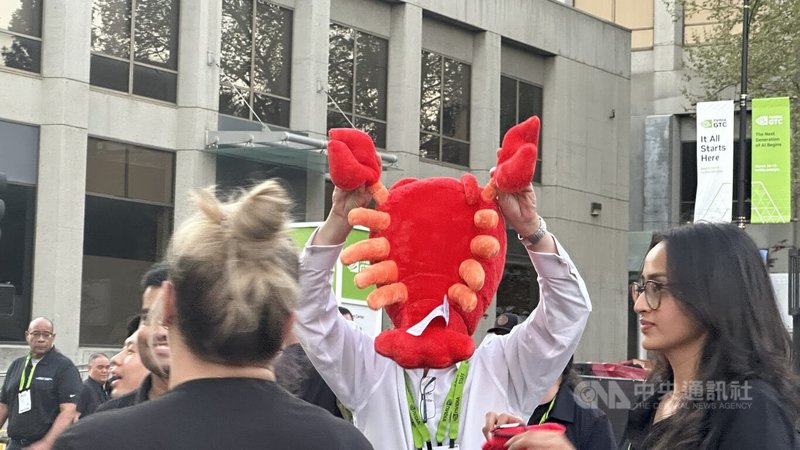輝達員工在GTC夜市高舉今年大會很夯的龍蝦玩偶。中央社記者張欣瑜聖荷西攝　115年3月18日