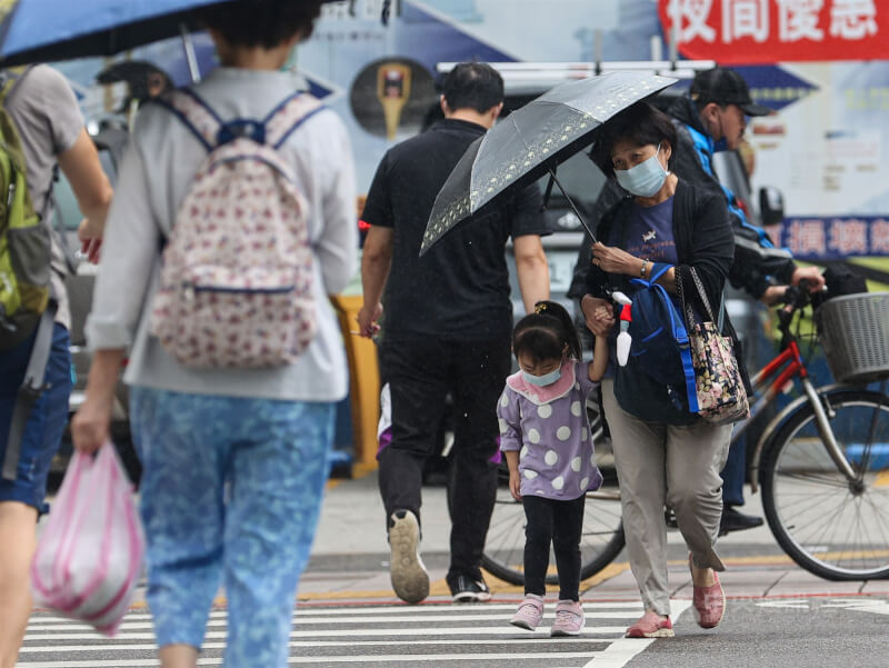 台北市飄雨，親子撐傘牽手過馬路。（中央社檔案照片）