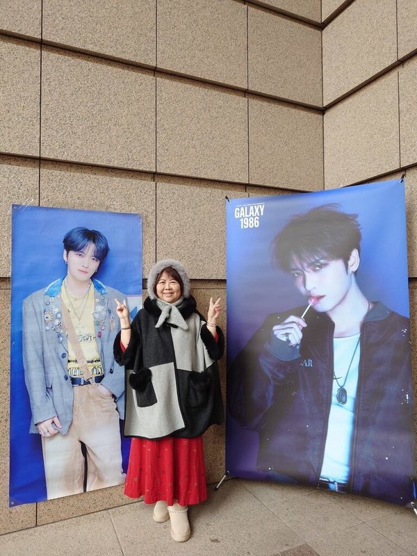 立下「每個月看一場演唱會」的目標,69歲退休護理師姚姐(化名)參加韓國歌手金在中演唱會,與大型海報合影。(讀者提供) 中央社記者陳婕翎傳真 115年3月22日