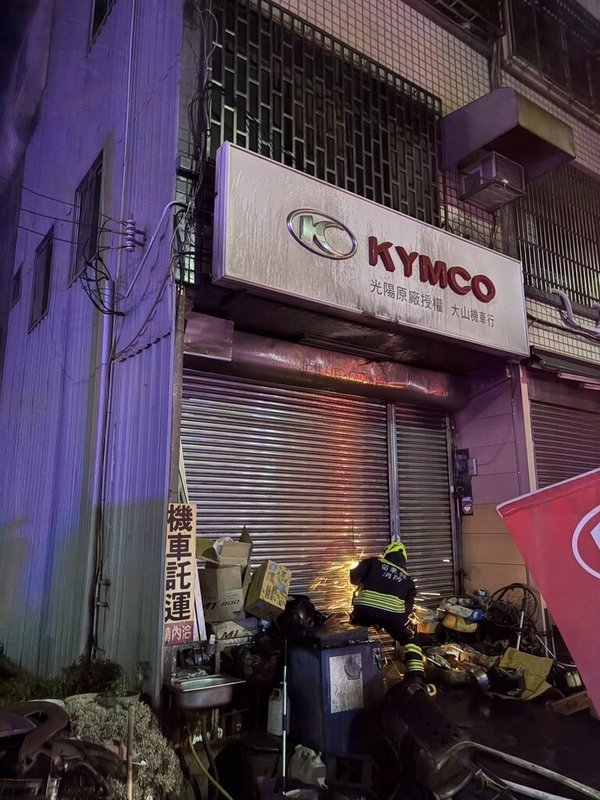 苗栗縣後龍鎮1間機車行21日晚間發生火警，消防獲報到場時，屋主已先將下肢癱瘓的兒子拉出家門，緊急破門進入搜救受困的屋主母親，已無生命跡象，祖孫2人送醫後1死1傷。（苗栗縣消防局提供）中央社記者魯鋼駿傳真 115年3月22日