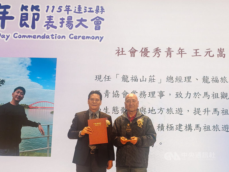 連江縣政府25日在南竿鄉舉辦115年青年節表揚大會，會中表揚3名社會優秀青年，獲選青年王元嵩由父親王樹欽（右）代為接受表揚。左為連江縣長王忠銘。中央社記者潘欣彤攝　115年3月25日