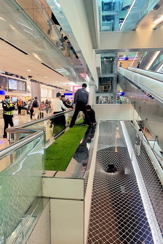 桃園國際機場25日中午發生7歲幼童在入境大廳自行跨越北側電扶梯圍籬跳下防墜網，後經警消協助脫困，桃機公司呼籲家長應隨時留意幼童動向，確保安全。（民眾提供）中央社記者吳睿騏桃園機場傳真　115年3月25日