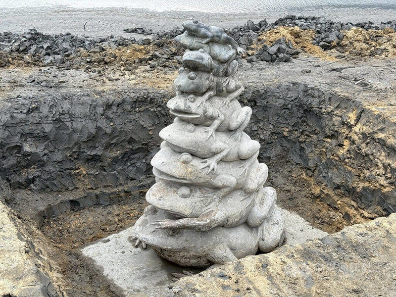 日月潭水庫主管機關台灣電力股份有限公司大觀發電廠派員清除「九蛙疊像」周邊乾硬泥土，讓青蛙疊羅漢銅雕完整露出。中央社記者蕭博陽南投縣攝　115年3月27日