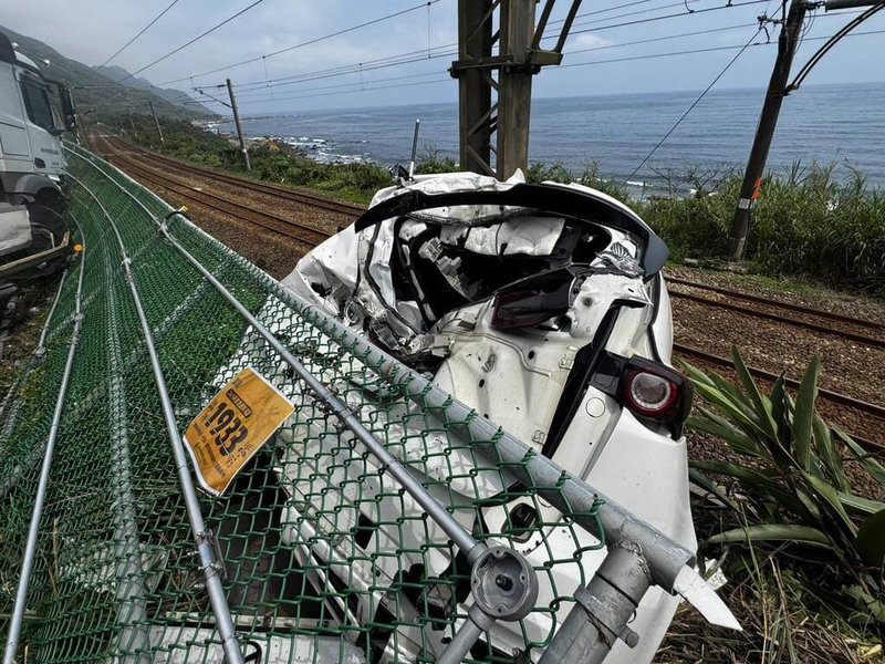 一輛曳引車30日中午行經宜蘭縣頭城鎮大里天公廟附近時前輪爆胎，失控追撞5輛自小客車，其中1輛自小客車（圖）衝過護欄卡在邊坡，導致路樹樹枝接觸台鐵電車線，台鐵班次因而延誤。（讀者提供）中央社記者王朝鈺傳真　115年3月30日