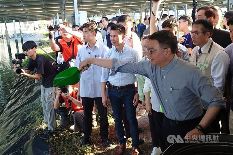 圖為行政院長卓榮泰（前右）先前參訪台南七股漁電共生案場，並體驗投放飼料。（中央社檔案照片）