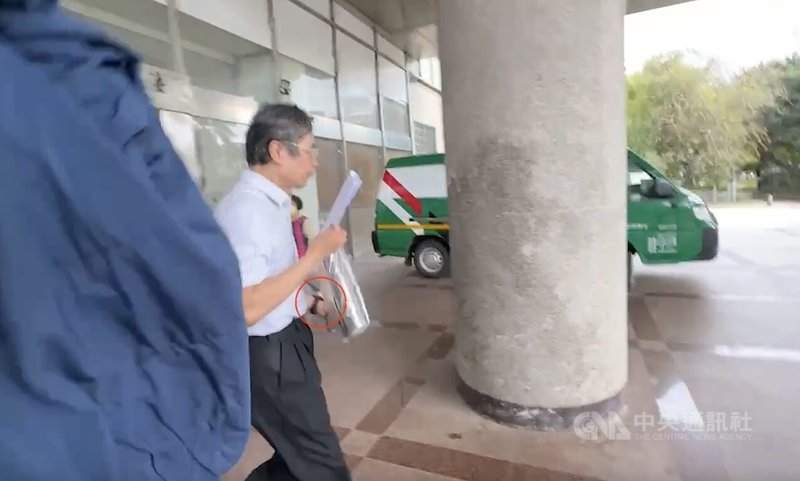 苗栗縣頭份市邱姓男醫師性騷診所女員工涉強制猥褻罪遭聲押，法院1日凌晨裁定以新台幣30萬元交保並實施科技監控。邱男下午步出法院時，左手已戴上黑色監控手環（紅圈處），一見媒體立即快閃。（翻攝畫面）中央社記者管瑞平傳真　115年4月1日