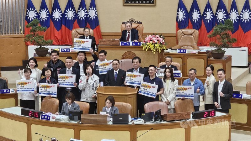 新北市長侯友宜（2排左5）1日在市議會宣布推動國中小學生免費營養午餐政策後，藍綠議員都表支持。圖為國民黨團持字卡到台前與侯友宜合影、高喊口號。中央社記者王鴻國攝　115年4月1日