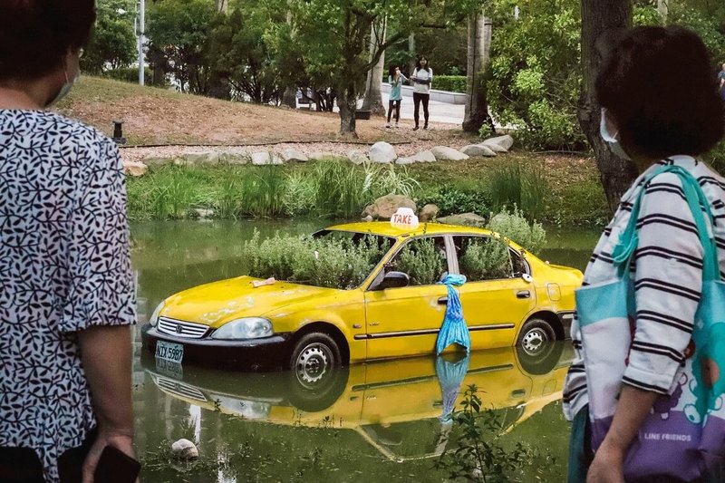 高雄市立美術館園區因一輛計程車泡在湖面上引發虛驚。高美館表示，這是台電公共藝術祭「奧拉之城III－未來已讀」展件之一，展覽4月3日登場，展期至6月7日。（高美館提供）中央社記者林巧璉傳真　115年4月2日