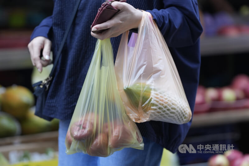 消費者2日在台北市北投區到市場用塑膠袋提著採買的蔬果。（中央社檔案照片）