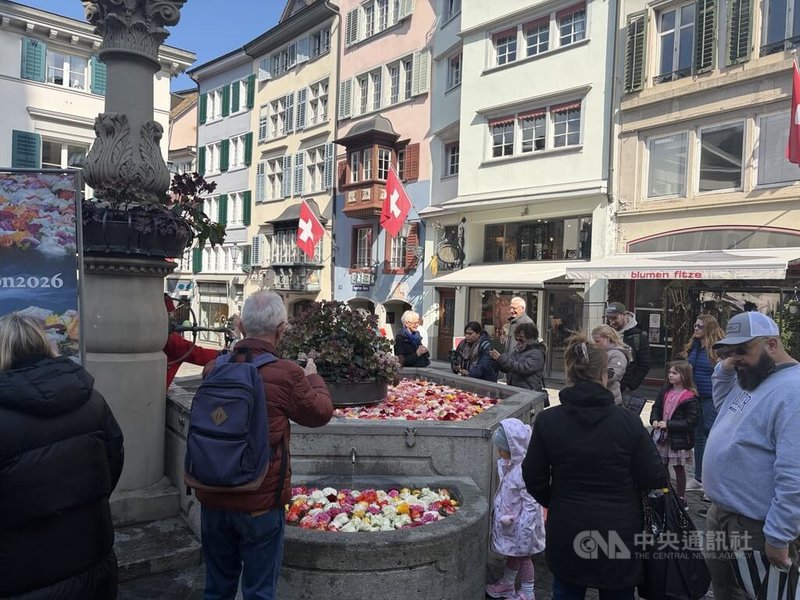 蘇黎世老城的玫瑰噴泉源自15年前花店保存婚禮剩花、布置水池的行動,照片中右側的Blumen Fitze花店是玫瑰噴泉最早發起的花店之一,以回收花材妝點店門口的噴泉,十多年來遊客絡繹不絕,創造善的循環。中央社記者郭芳君蘇黎世攝 115年4月4日